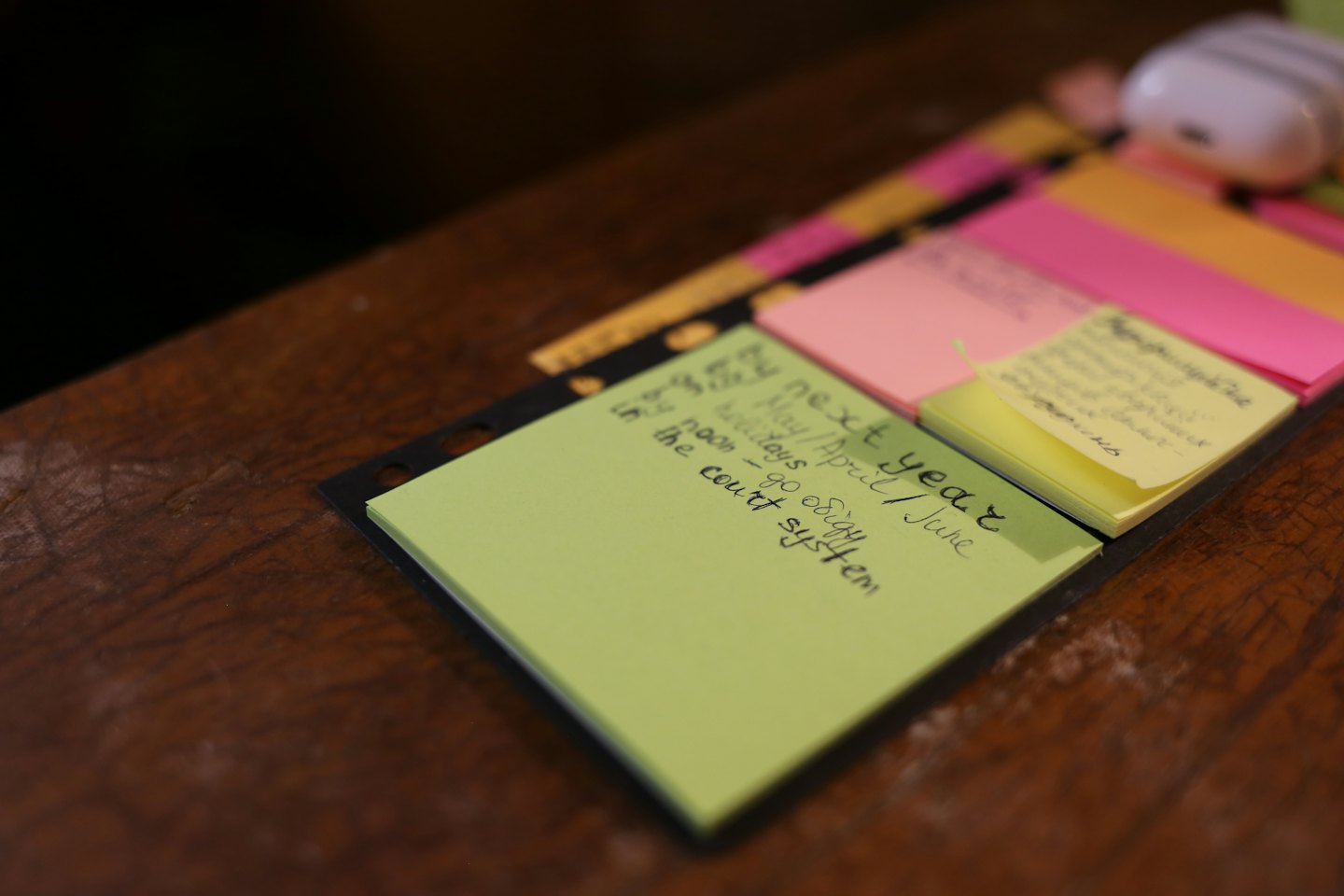 Desk organizer with colorful sticky notes on a wooden surface.