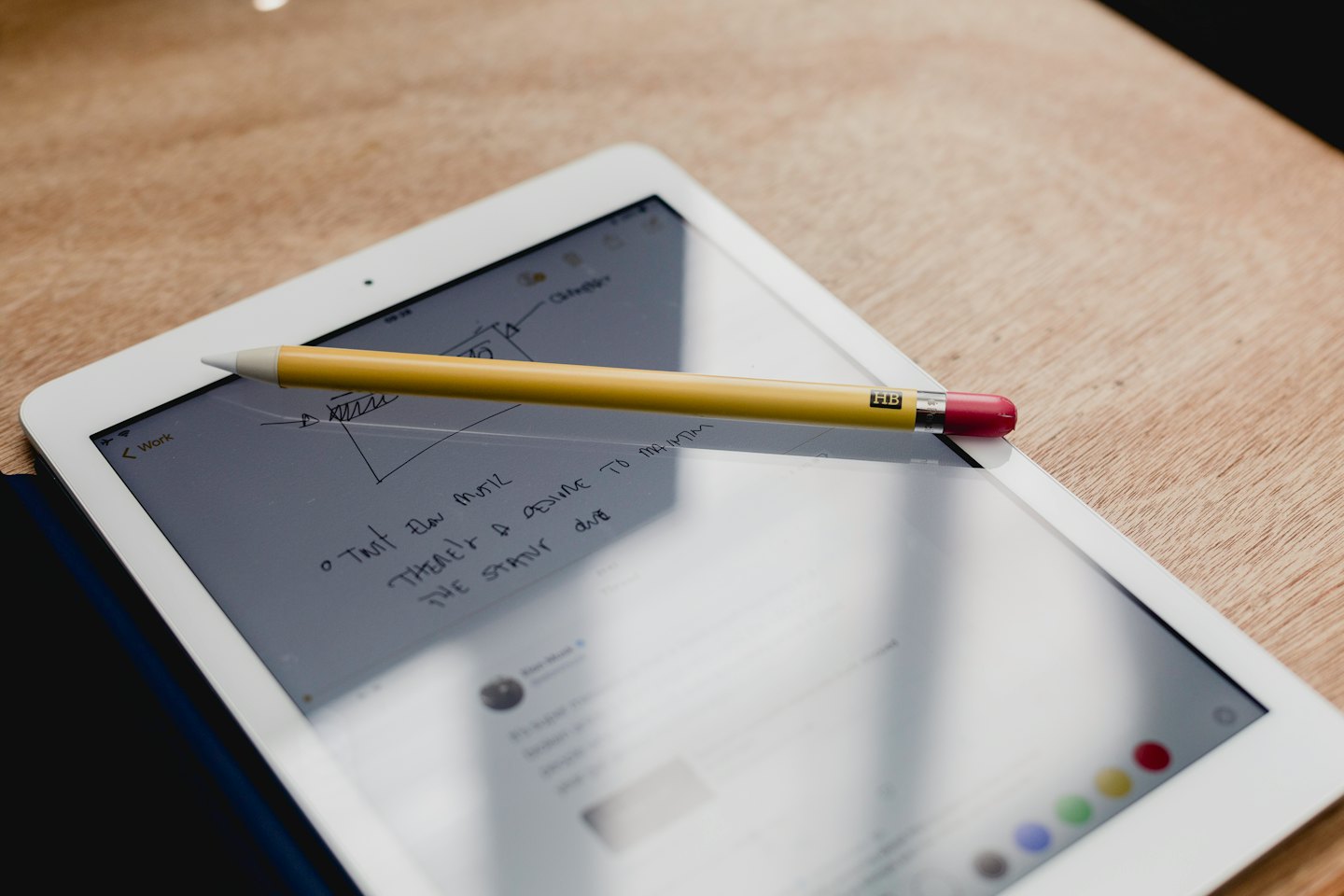 Tablet with notes and stylus on a wooden table.